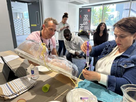 A group of people learn how to use a tube feeding model