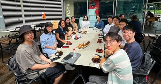 Students gathered at a long table with coffees