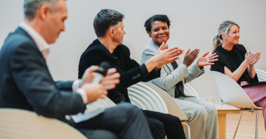 Image of four people on a panel, clapping