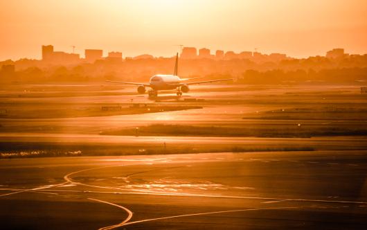 Plane on runway at sunset. Adobe Stock