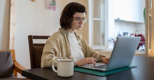 A woman with glasses focussing on work on a laptop