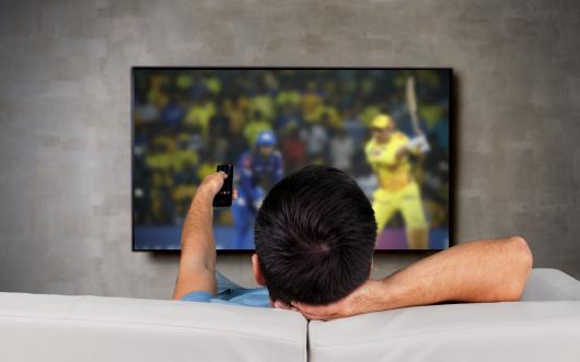 man watching cricket on TV