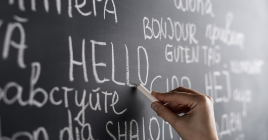 A person writing different languages on a blackboard.