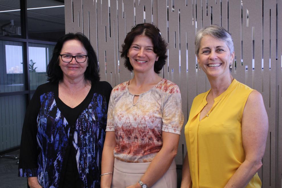 three female academics standing in front of a light coloured screen
