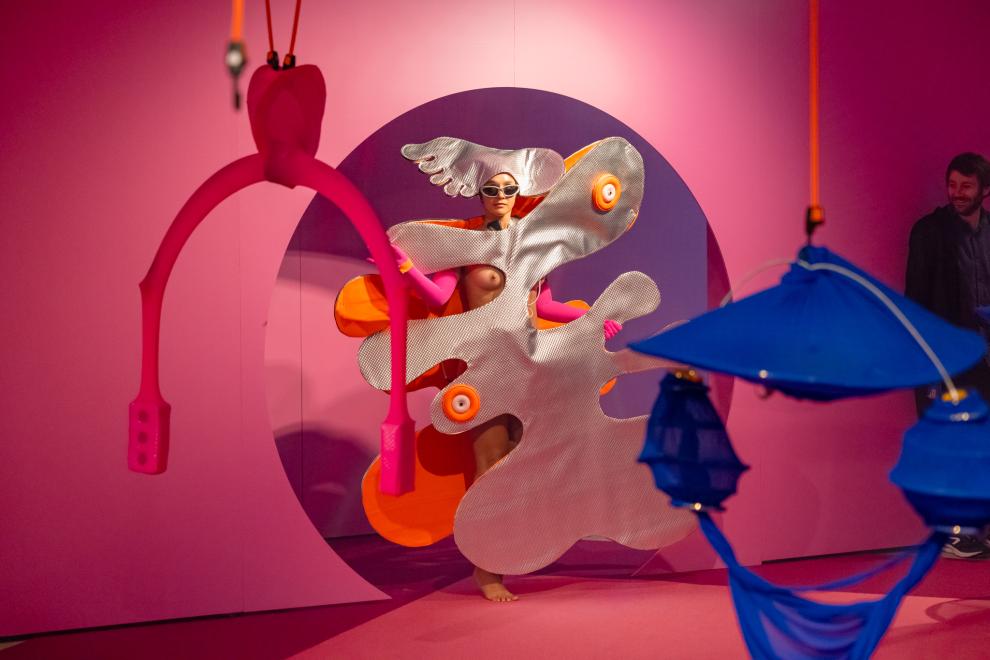 A person in a silver costume emerges from a round doorway