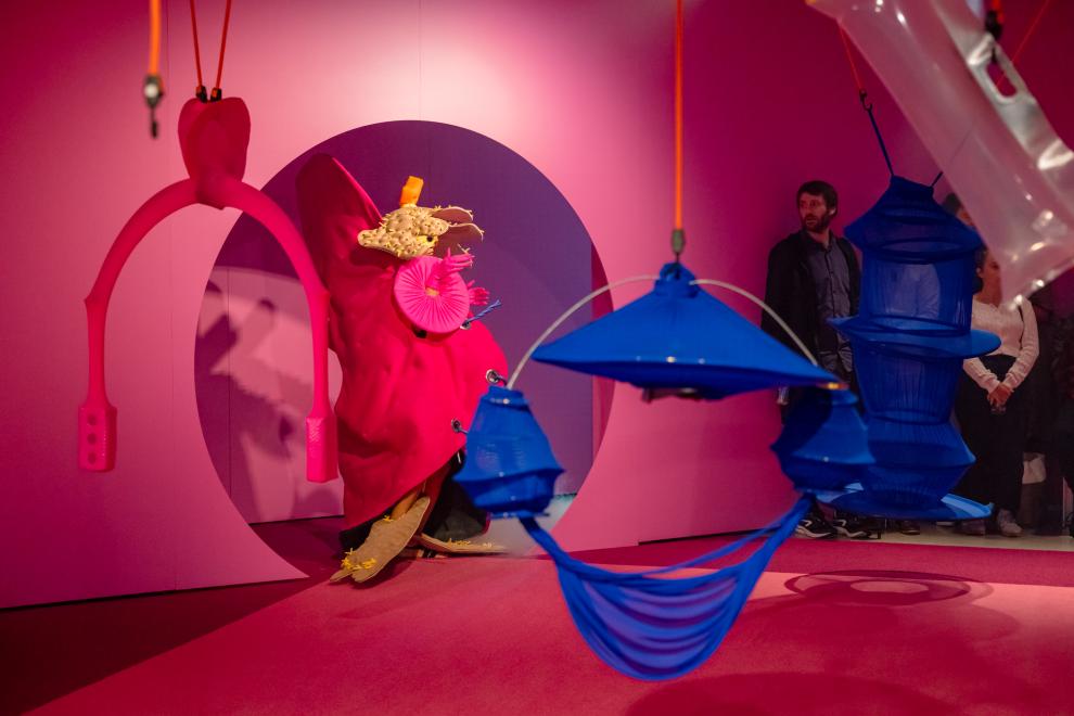 A person in a pink costume emerges from a round doorway