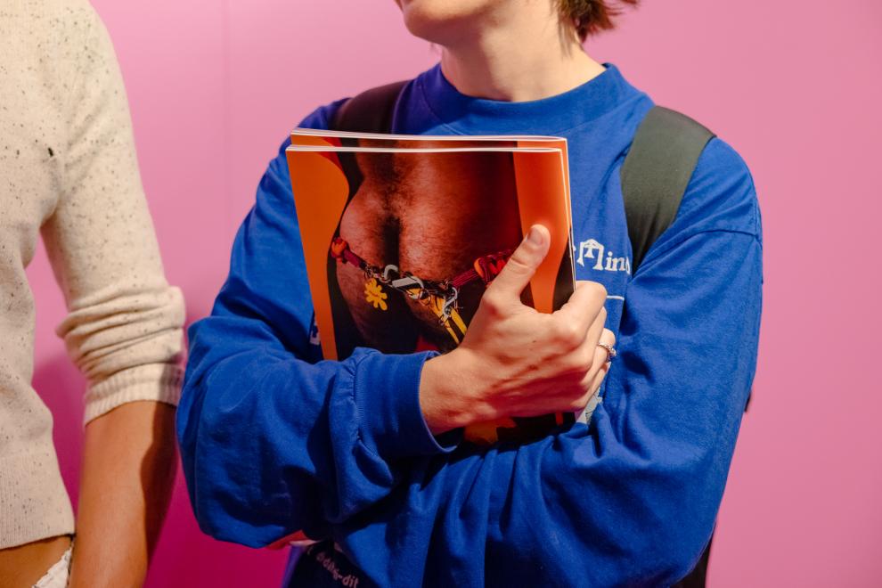 A person in a blue jumper holds a book with a bum on the back cover
