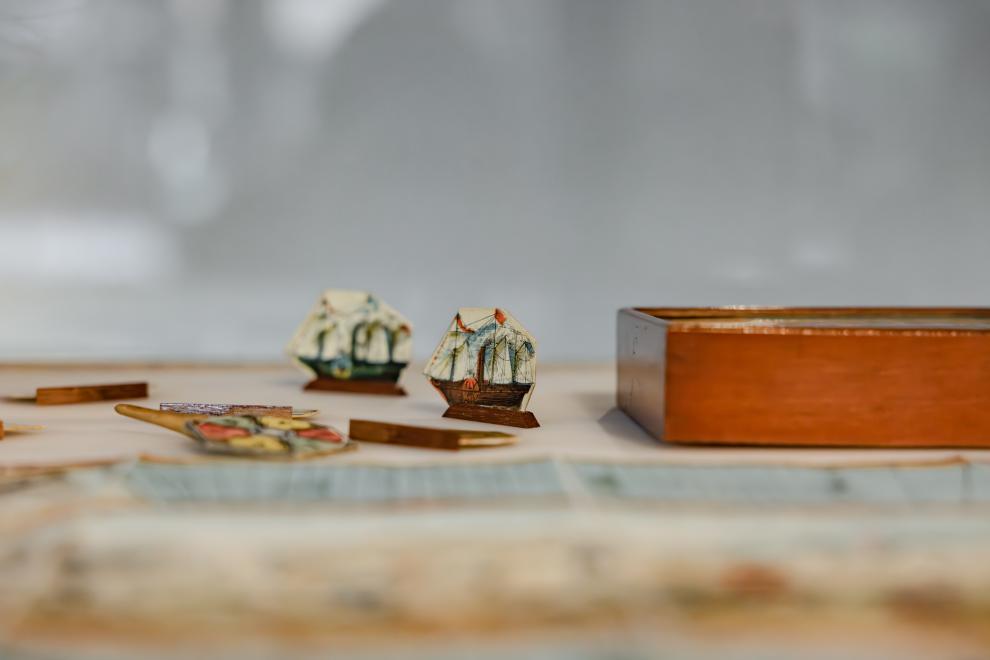 A close up view of children's game pieces; two paper ships and a spinning wheel