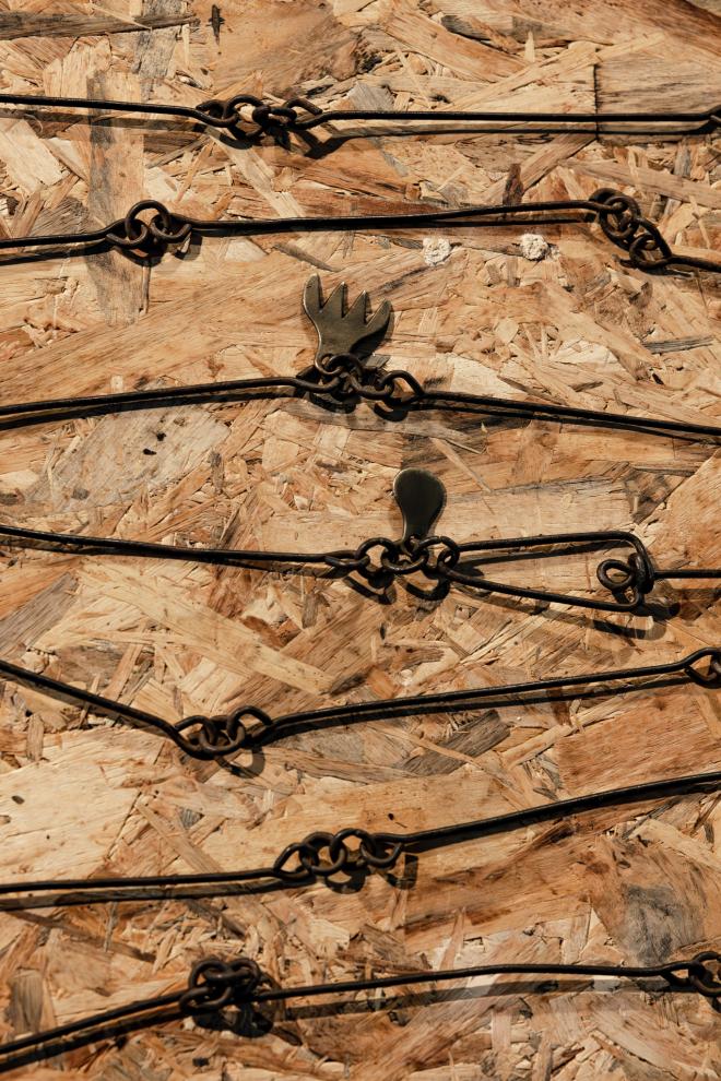 A gunters Chain, used for measuring land, sits atop a wooden table. 