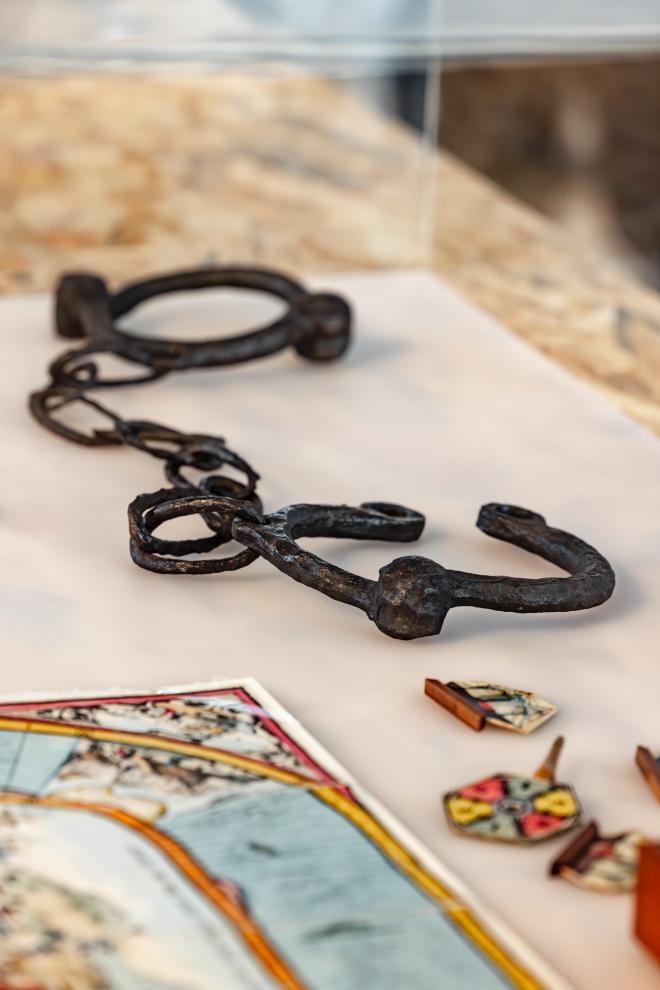 A view of leg manacles and a children's game in an acrylic box