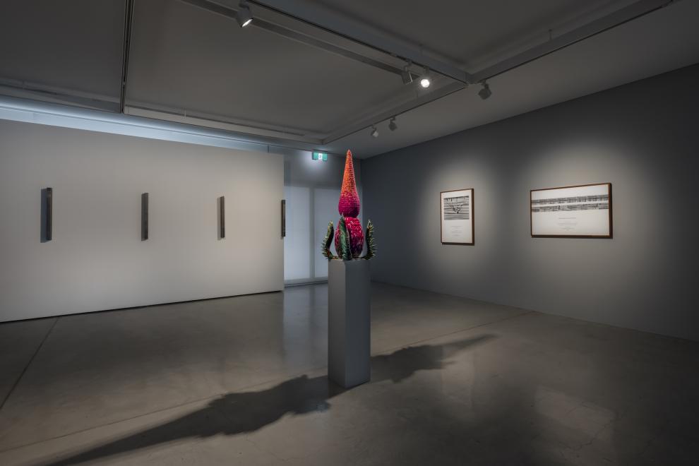 An open plan gallery space with grey walls and artworks on each wall