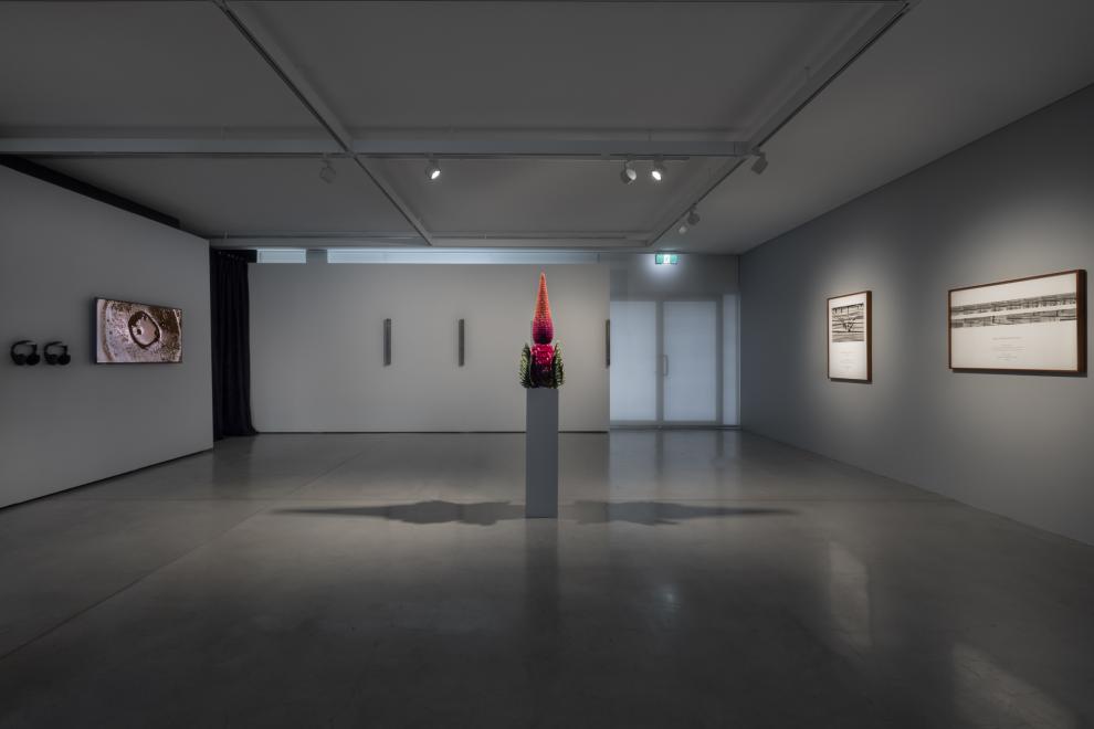 An open plan gallery space with grey walls and artworks on each wall