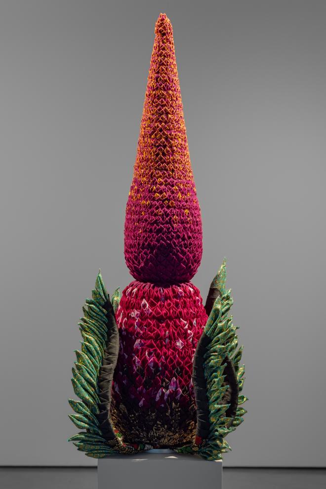An orange, pink and green sculptural object on a plinth