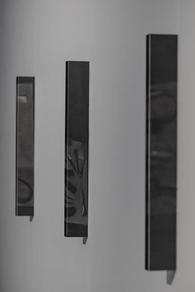 Three graphite and paper artworks on a white wall