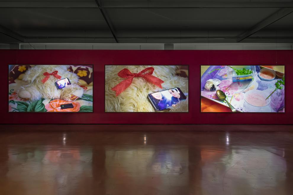 A three channel video work in a gallery with red walls 