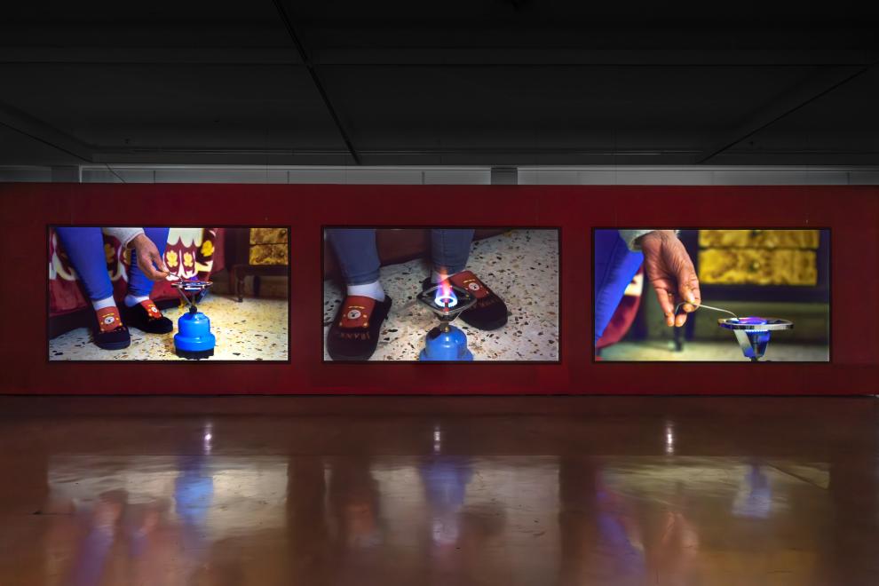 A three channel video work in a gallery with red walls 