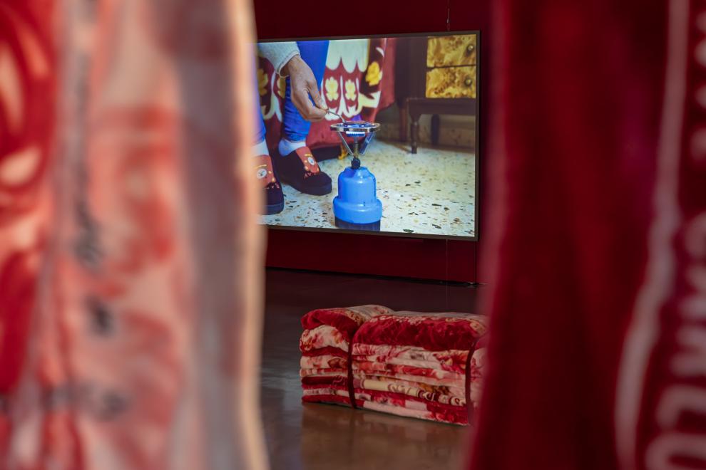 A three channel video work in a gallery with red walls 