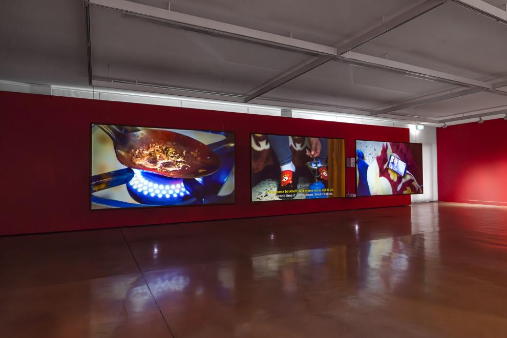 A three channel video work in a gallery with red walls 