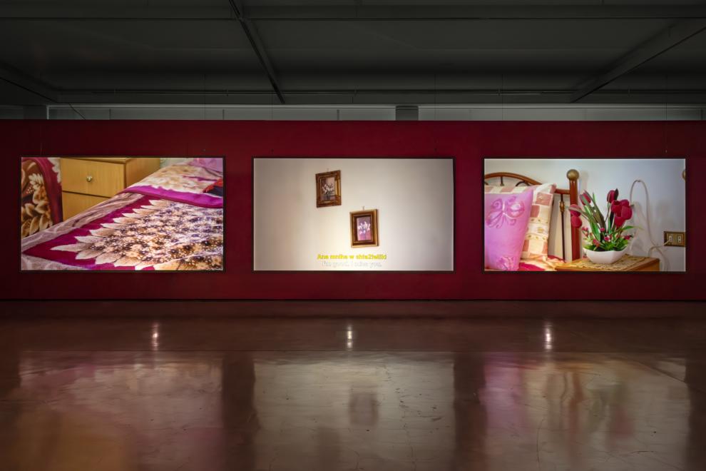 A three channel video work in a gallery with red walls 