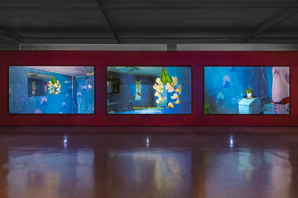 A three channel video work in a gallery with red walls 