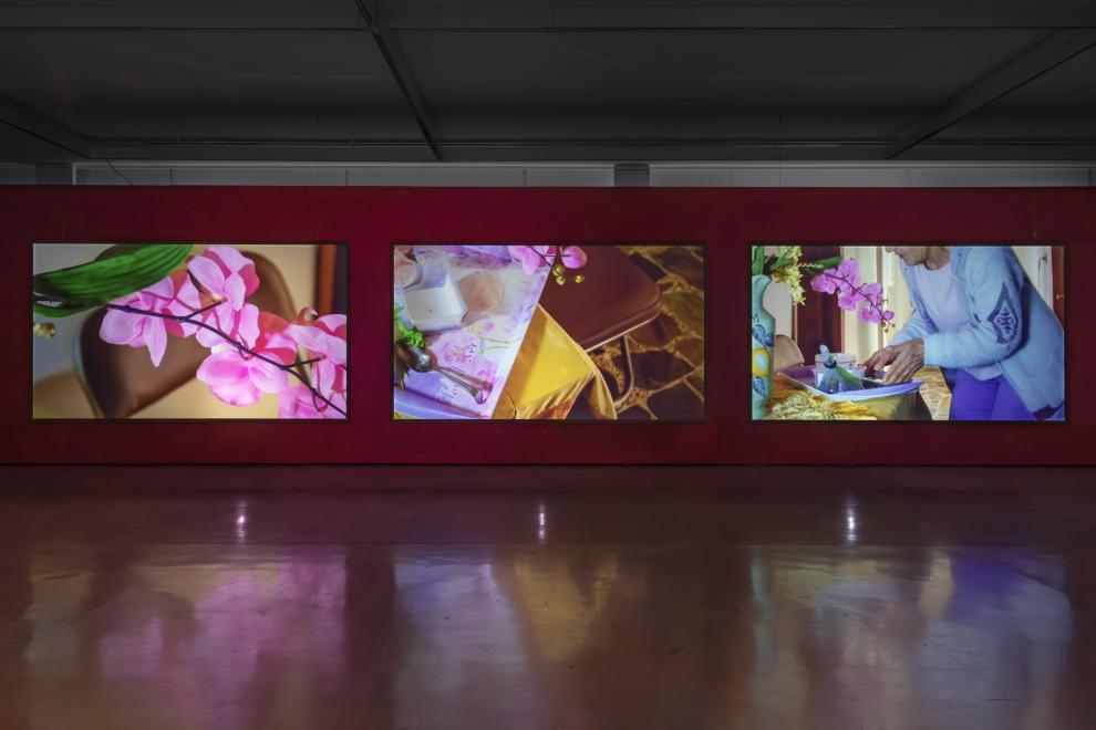 A three channel video work in a gallery with red walls 