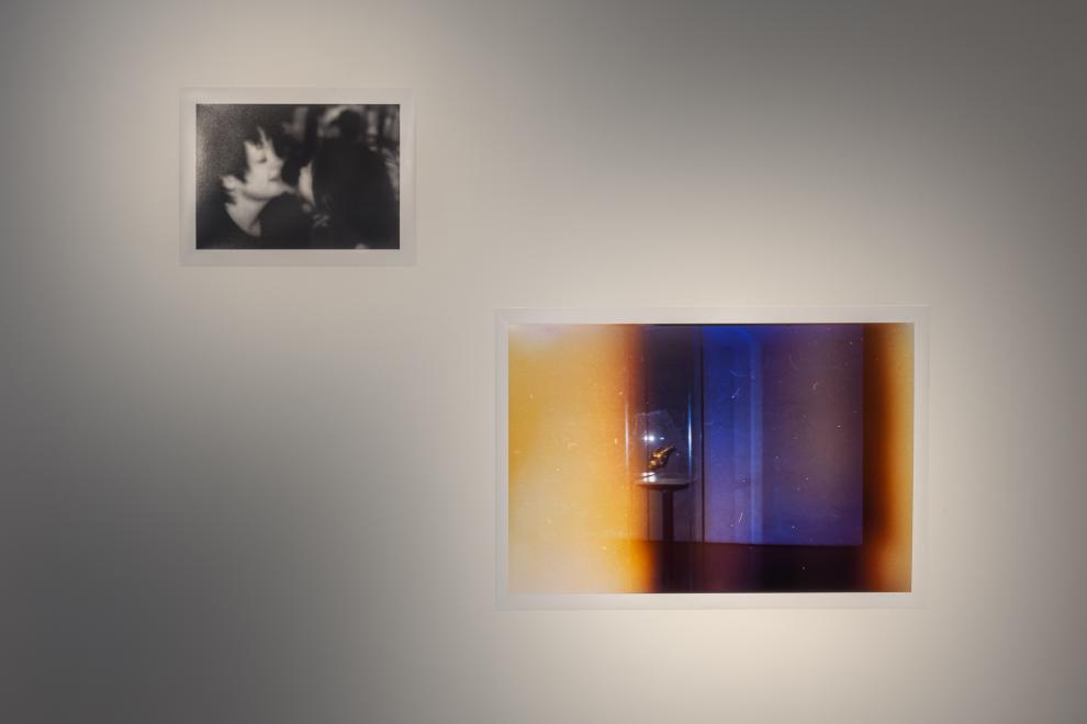 A photograph showing an oversize reproduction of an ‘end of roll’ exposure where the image is only partly visible and disappears into a wash of yellow, white and red. The recognisable part of the photograph is a far-away shot of a golden conch in a museum vitrine, placed in a dark blue room.