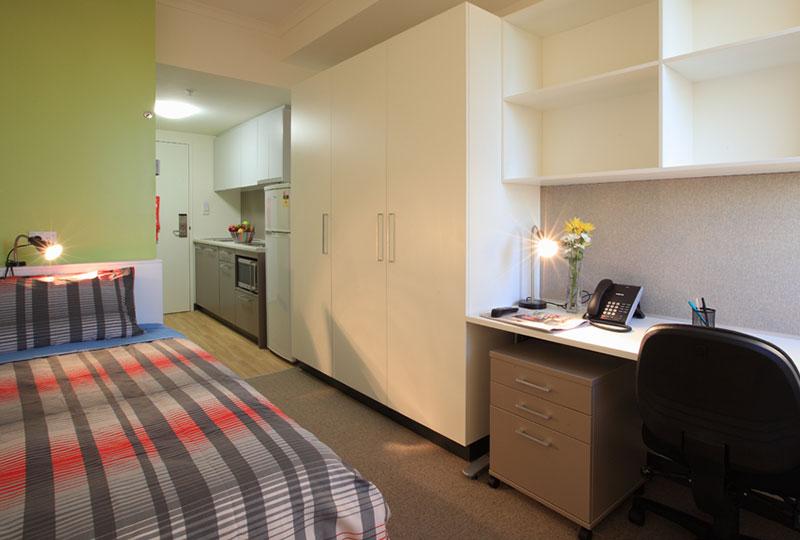 Room with view of bed, kitchen and desk