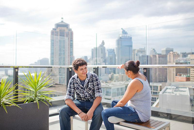 Two people chatting with view of buildings in the background