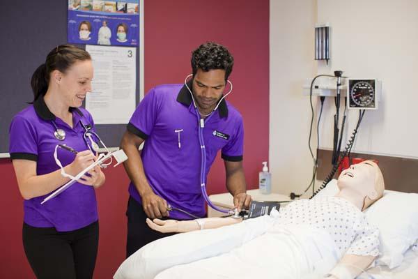 Students using a sphygmomanometer and stethoscope