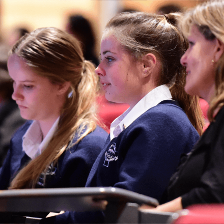 Two female high school students in uniform sitting with their Mother