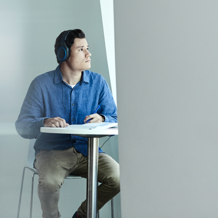 A male student sitting at a desk with headphones on