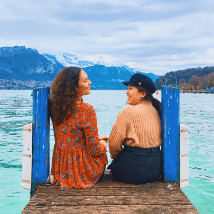 Two ICS female students sitting and laughing on a beach in Costa Rica