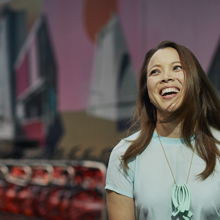 Female student smiling in front of a mural wall