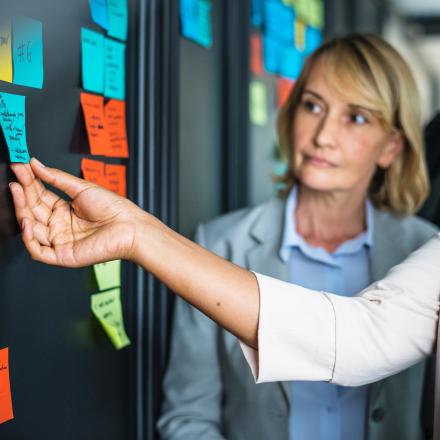 Woman reading a post it note that is stuck to the wall