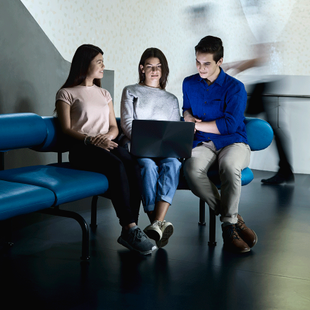 Two female and one male student sharing a laptop