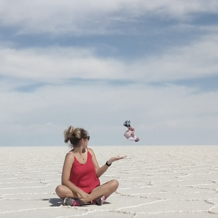 Steph sitting in the desert as a boy backflips next to her