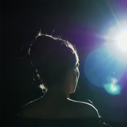 Woman on dark stage with stage lighting