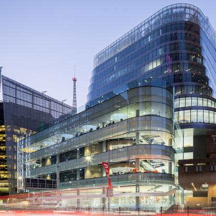 UTS Central viewed from Broadway at twilight, illuminated from inside, with the blur of headlights from passing traffic.