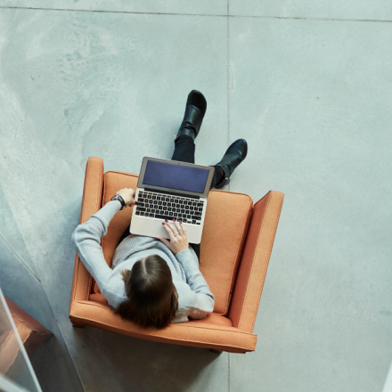 A student sitting in a chair working on a laptop