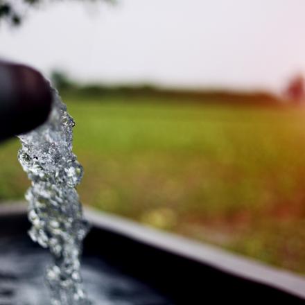 Image of water flowing from pipe into an irrigation channel