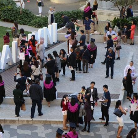 Group of UTS graduates in academic gowns being photographed