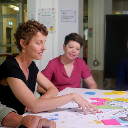 Smiling colleagues working together around table with coloured post-it notes