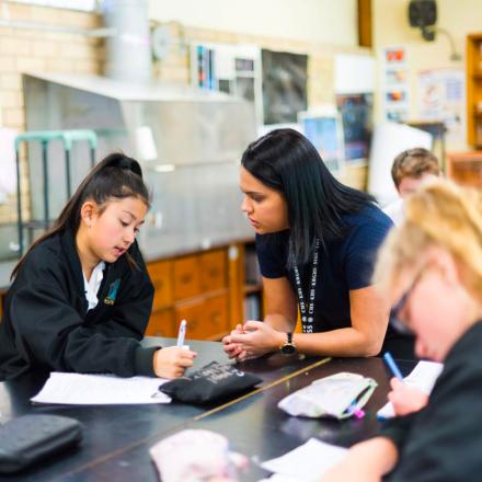 Teacher helping a student in classroom scene