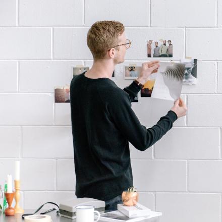 Man placing images on brick wall