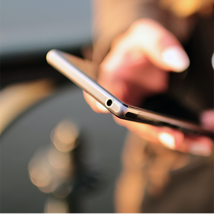 Hand holding mobile phone and coffee cup