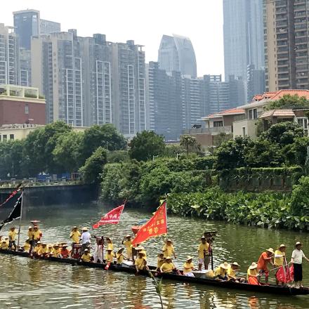 Traditional boat, meandering river, city backdrop