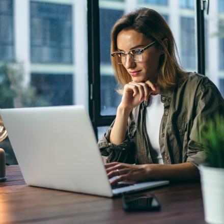 A woman sit pensively at a computer.