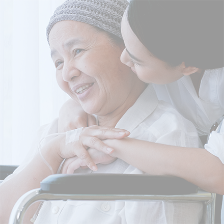 Mother in wheelchair wearing headscarf hugged by daughter