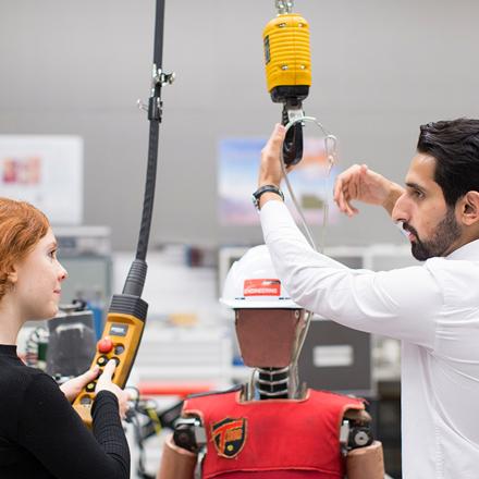 Two students working a hoist in the lab