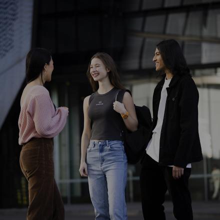 Three student chat outside Building 11